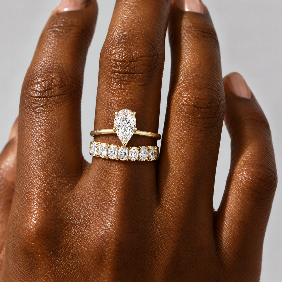 Pear Solitaire Ring stacked with an oval eternity band, close-up