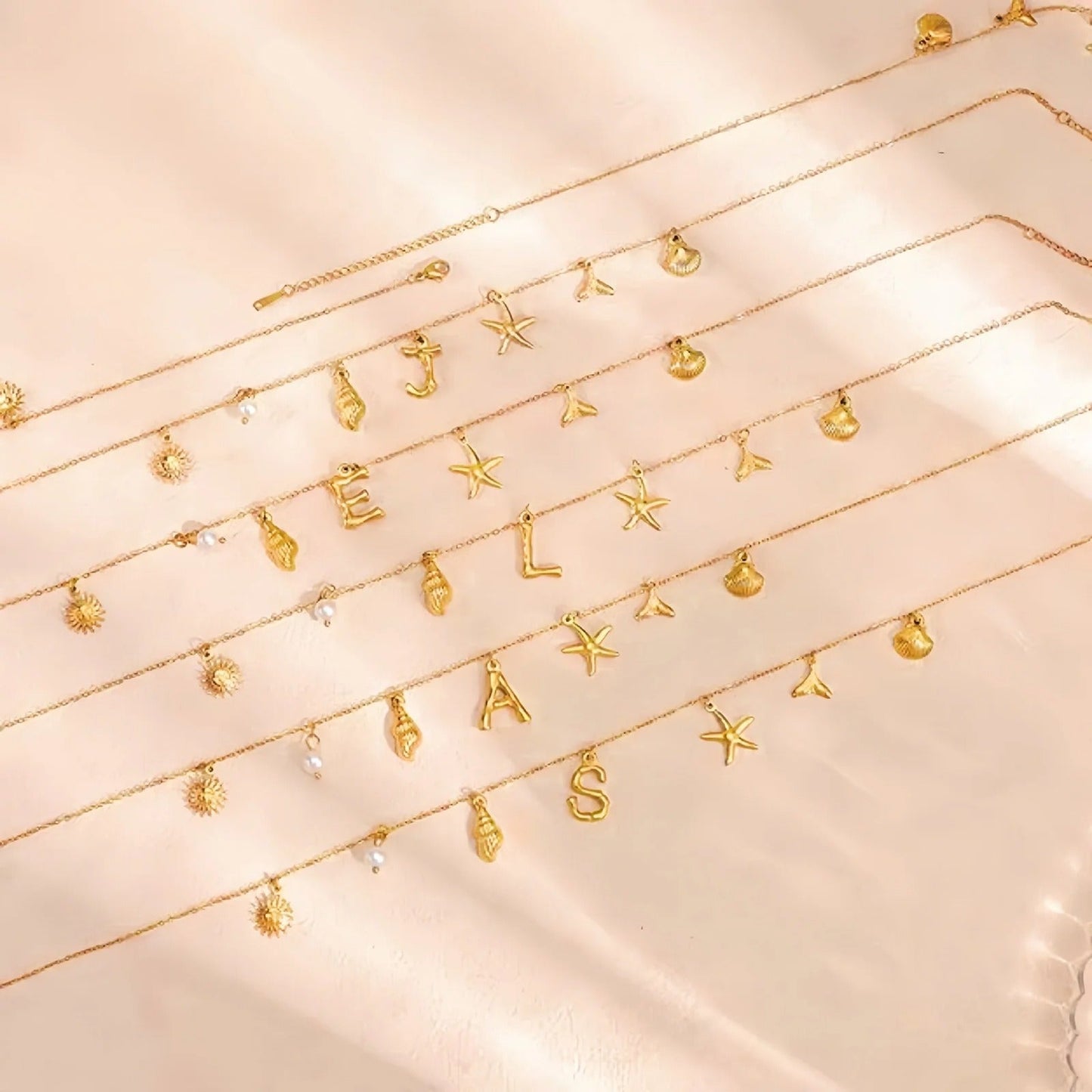 Collana con iniziale a forma di stella marina e conchiglia