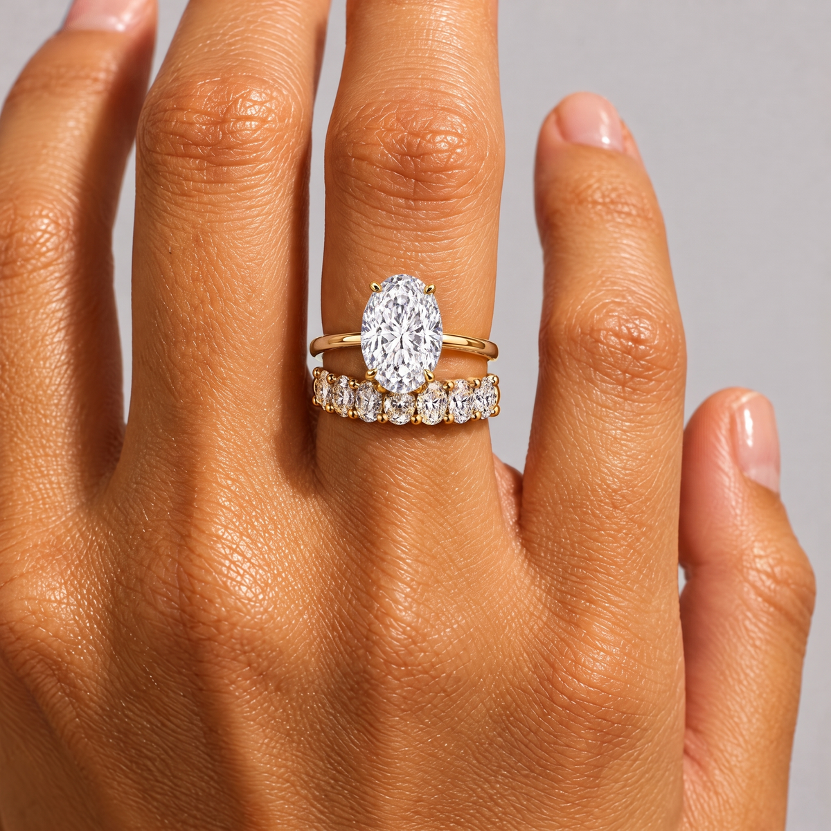 Grand Oval Solitaire Ring stacked with an oval eternity band, close-up