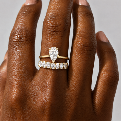 Pear Solitaire Ring stacked with an oval eternity band, close-up