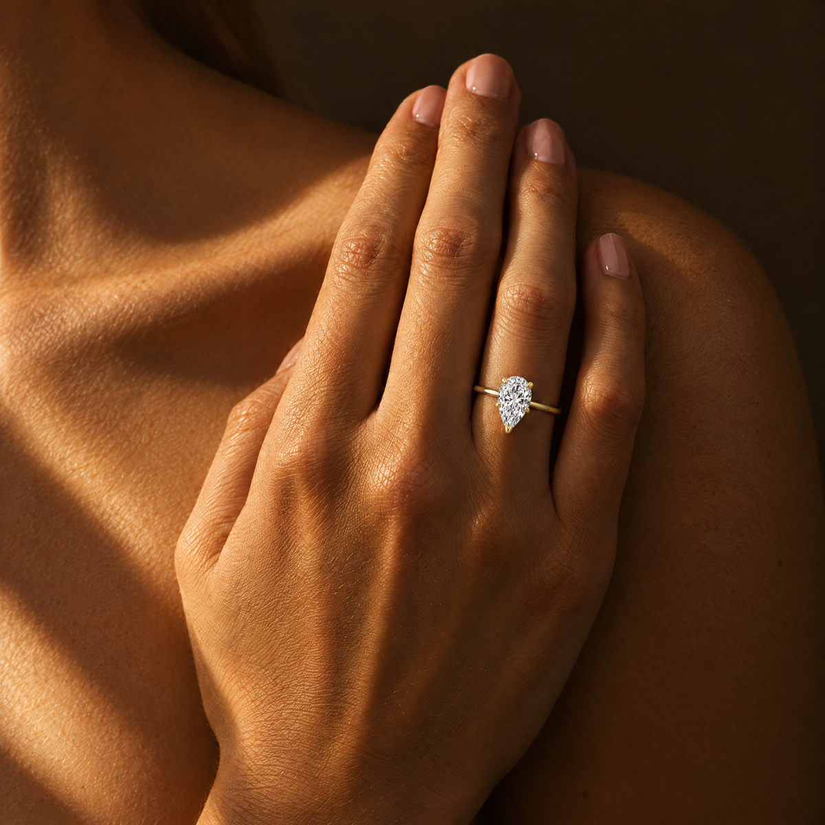 Pear Solitaire Ring worn on the hand in warm light