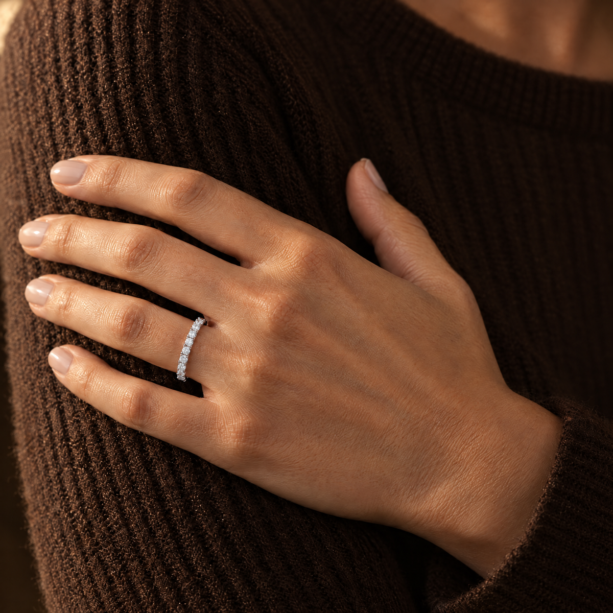 Silver eternity band ring worn with a knit